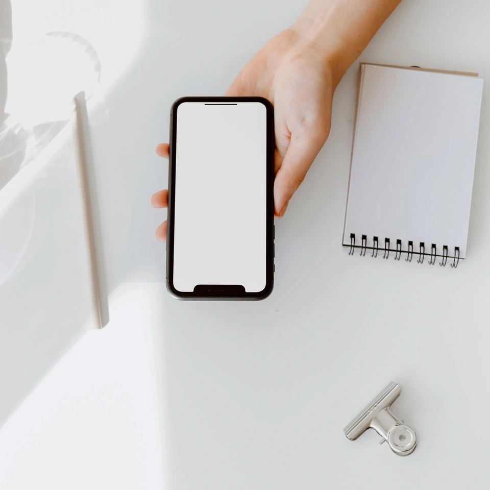 Hand holding a phone beside a notebook; general communication scene